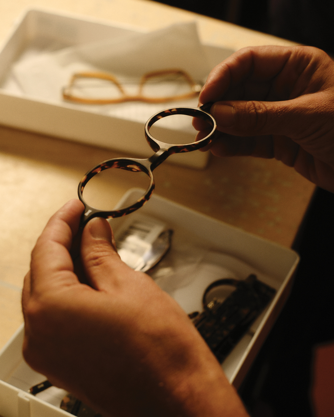 Hands examining a pair of Cubitts tortoiseshell frames